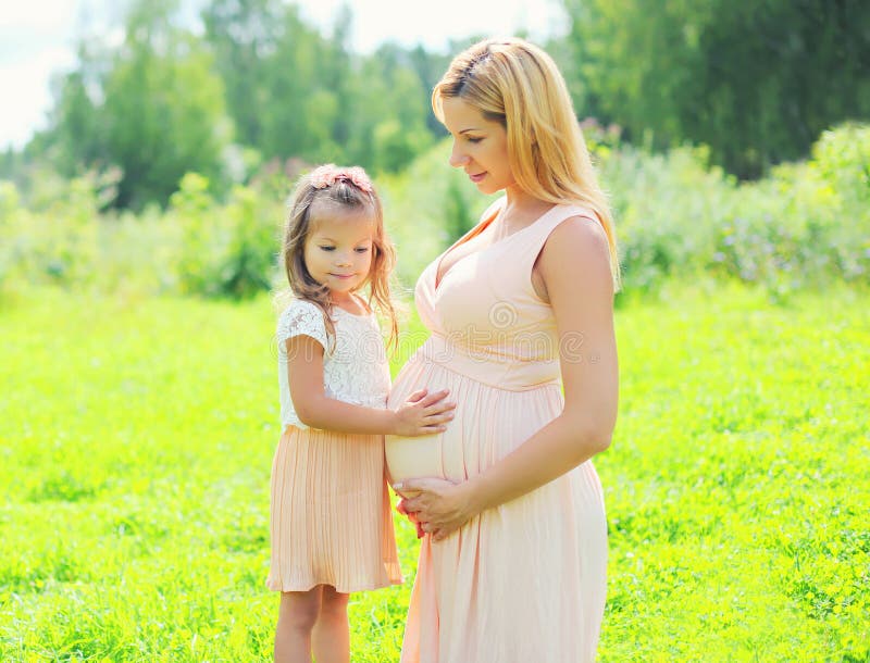 A mulher gravida feliz, filha da criança pequena toca na mãe da barriga imagens de stock royalty free A mulher gravida feliz, filha da criança pequena toca na mãe da barriga imagens de stock royalty free