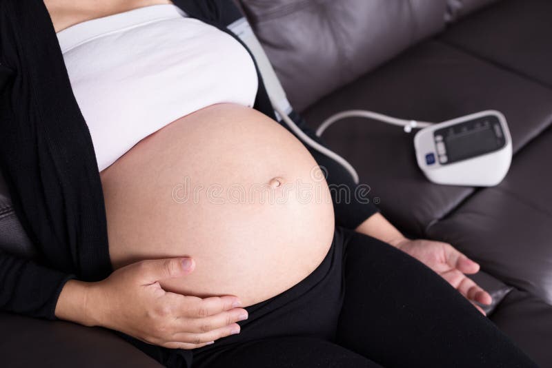 A mulher gravida mede a pressão sanguínea imagem de stock A mulher gravida mede a pressão sanguínea imagem de stock