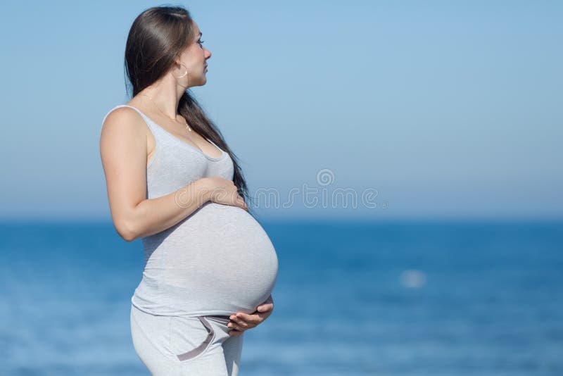 Mulher Grávida De Biquíni De Onepécia Vermelha Descansando No Mar Foto
