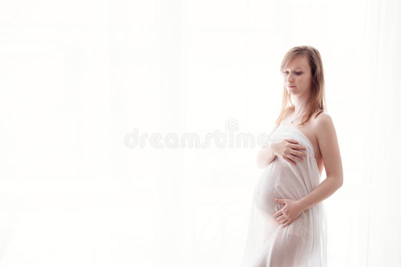 Mulher gravida nova bonita envolvida na tela branca fotografia de stock Mulher gravida nova bonita envolvida na tela branca fotografia de stock