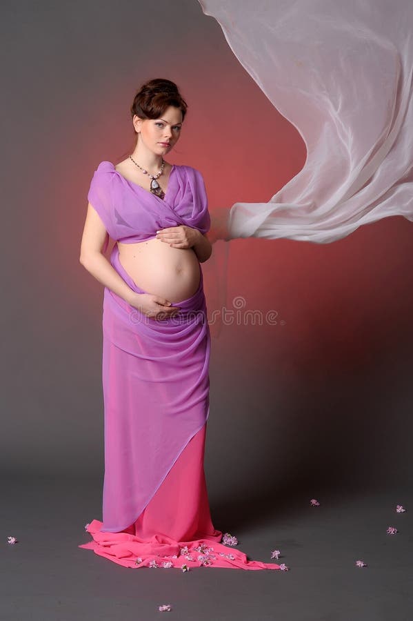 Mulher gravida nova no tou cor-de-rosa elegante do vestido fotografia de stock Mulher gravida nova no tou cor-de-rosa elegante do vestido fotografia de stock