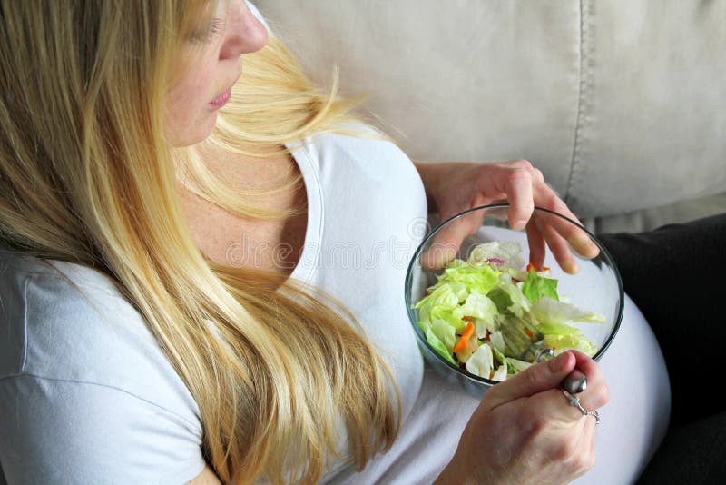 Mulher gravida nova saudável que come uma salada verde da folha fotografia de stock royalty free Mulher gravida nova saudável que come uma salada verde da folha fotografia de stock royalty free