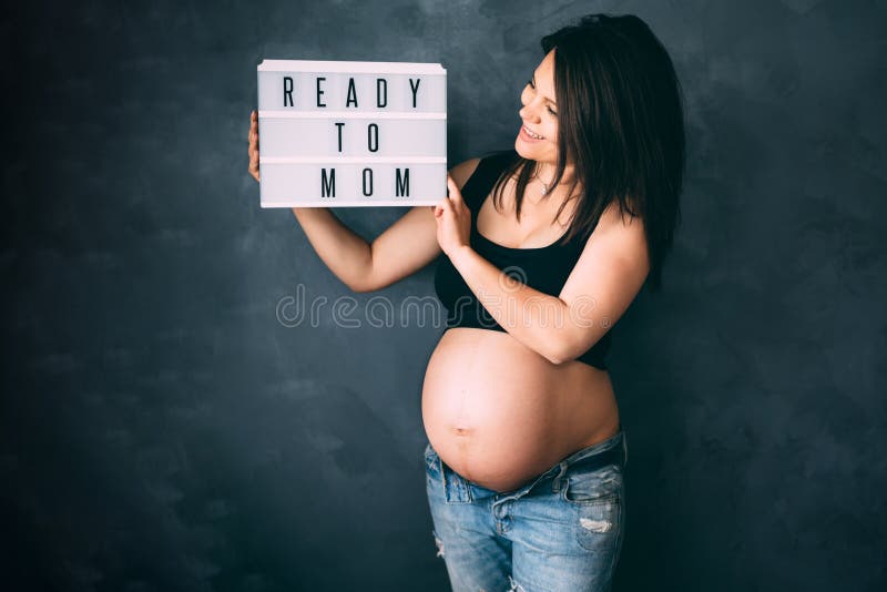 Mulher gravida que aprecia a vida, sorrindo e levantando para a câmera com barriga grande foto de stock Mulher gravida que aprecia a vida, sorrindo e levantando para a câmera com barriga grande foto de stock