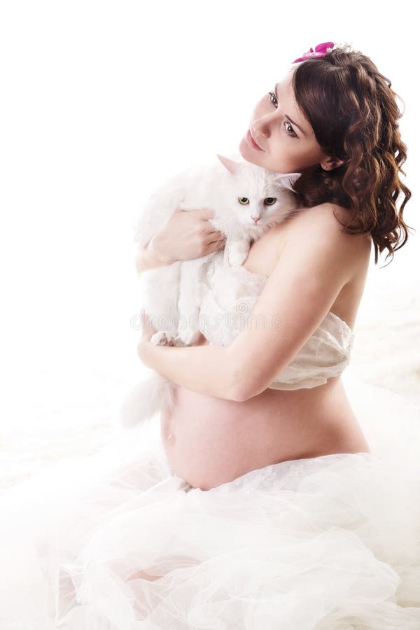 Mulher gravida que prende o gato peludo branco.