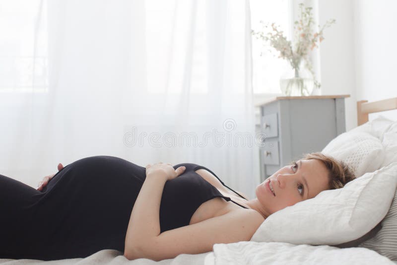 Mulher gravida sonhadora que encontra-se na cama fotografia de stock Mulher gravida sonhadora que encontra-se na cama fotografia de stock