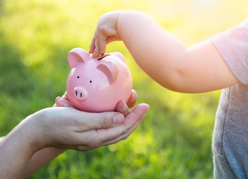 A mulher guarda o mealheiro quando o bebê puser moedas para dentro fotografia de stock A mulher guarda o mealheiro quando o bebê puser moedas para dentro fotografia de stock
