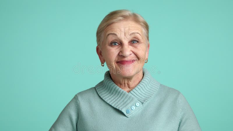 Mulher idosa excitada com cabelo loiro curto sorrindo mostrando o estúdio