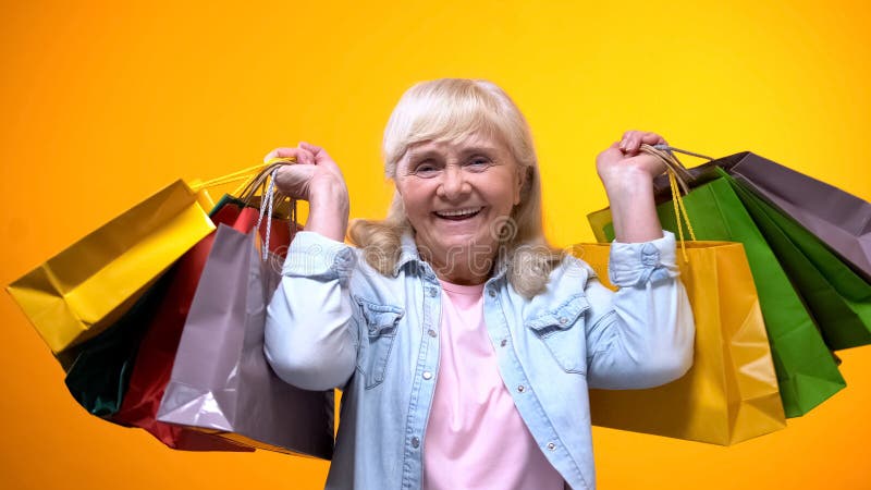 Mulher idosa feliz que mostra muitos sacos de compras, tempo de lazer, gastar dinheiro imagens de stock royalty free Mulher idosa feliz que mostra muitos sacos de compras, tempo de lazer, gastar dinheiro imagens de stock royalty free