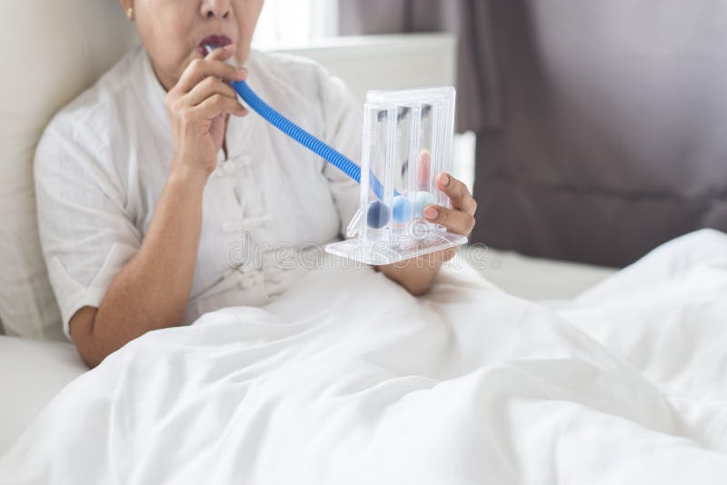 Mulher idosa paciente que usa o incentivespirometer ou as três bolas para para estimular o pulmão na sala fotos de stock Mulher idosa paciente que usa o incentivespirometer ou as três bolas para para estimular o pulmão na sala fotos de stock