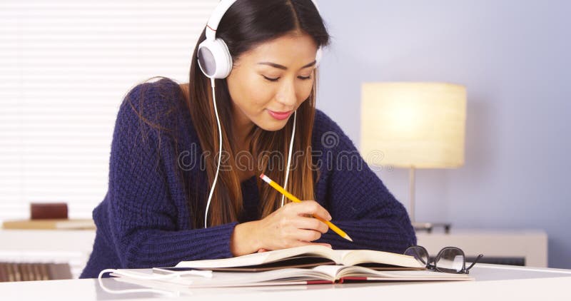 Mulher japonesa que escuta a música ao fazer trabalhos de casa foto de stock Mulher japonesa que escuta a música ao fazer trabalhos de casa foto de stock