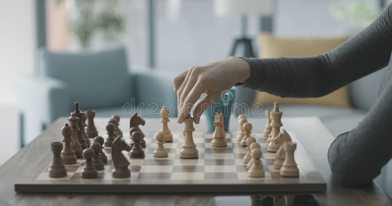 Jovem Mulher Olhando Para As Peças De Xadrez No Tabuleiro E Fazendo  Movimento Enquanto Joga Jogo De Tabuleiro De Xadrez Em Casa Sozinho Foto  Royalty Free, Gravuras, Imagens e Banco de fotografias.