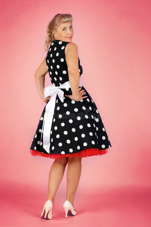 Mulher loura bonita em um vestido do às bolinhas flirty sobre seu ombro, estilo do pino-acima em um fundo cor-de-rosa fotos de stock Mulher loura bonita em um vestido do às bolinhas flirty sobre seu ombro, estilo do pino-acima em um fundo cor-de-rosa fotos de stock