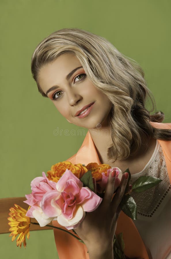 Mulher loura bonita na laranja que guarda flores fotografia de stock royalty free Mulher loura bonita na laranja que guarda flores fotografia de stock royalty free