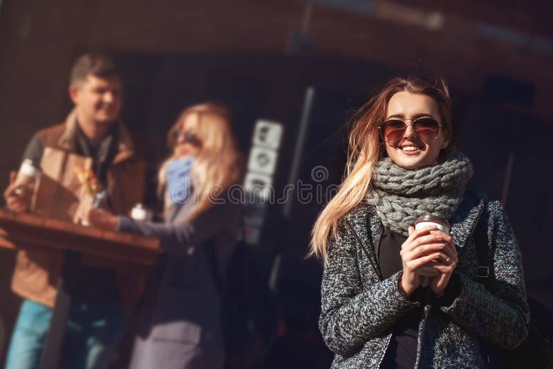 Mulher loura nova bonita nos óculos de sol que guardam o copo e o croissant de café e que olham o sol com smil fotos de stock Mulher loura nova bonita nos óculos de sol que guardam o copo e o croissant de café e que olham o sol com smil fotos de stock