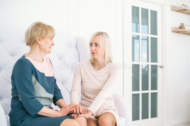Mulher loura nova e sua mãe superior que sentam-se no sofá foto de stock Mulher loura nova e sua mãe superior que sentam-se no sofá foto de stock