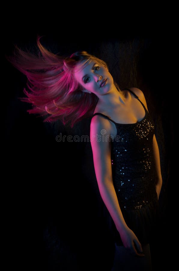 Mulher loura 'sexy' que passa rapidamente a ela em luzes coloridas contra um fundo preto fotografia de stock Mulher loura 'sexy' que passa rapidamente a ela em luzes coloridas contra um fundo preto fotografia de stock