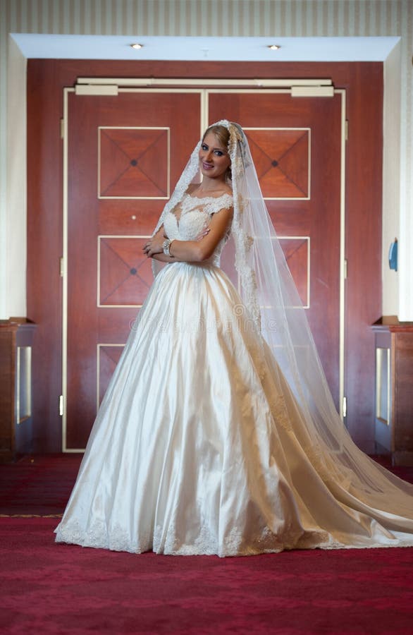 Mulher luxuoso bonita nova no vestido de casamento que levanta no interior luxuoso Noiva elegante lindo com véu longo Comprimento fotos de stock royalty free Mulher luxuoso bonita nova no vestido de casamento que levanta no interior luxuoso Noiva elegante lindo com véu longo Comprimento fotos de stock royalty free