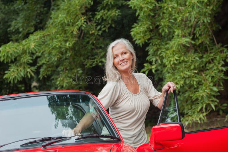 Mulher madura alegre que obtém fora seu convertible imagens de stock Mulher madura alegre que obtém fora seu convertible imagens de stock