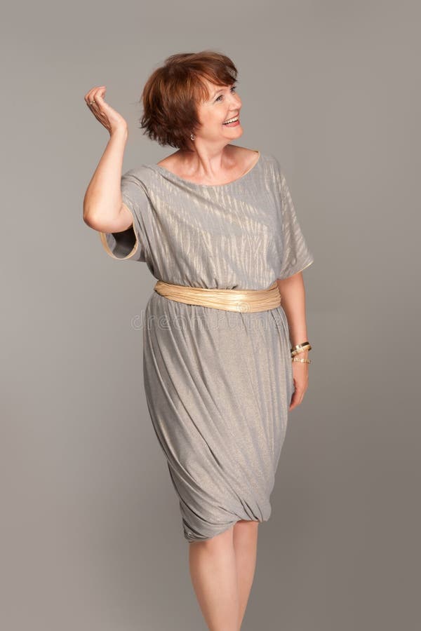 Mulher madura elegante bonita no vestido cinzento fotografia de stock royalty free Mulher madura elegante bonita no vestido cinzento fotografia de stock royalty free