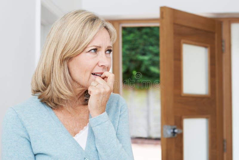 Mature Woman Suffering From Agoraphobia Looking Out Of Open Door. Mature Woman Suffering From Agoraphobia Looking Out Of Open Door