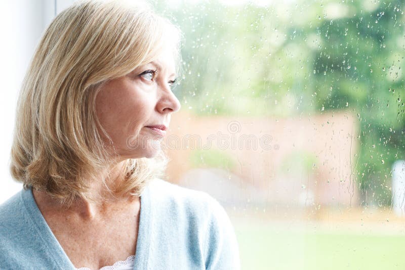 Mulher madura triste que sofre da agorafobia que olha fora de Windo foto de stock Mulher madura triste que sofre da agorafobia que olha fora de Windo foto de stock