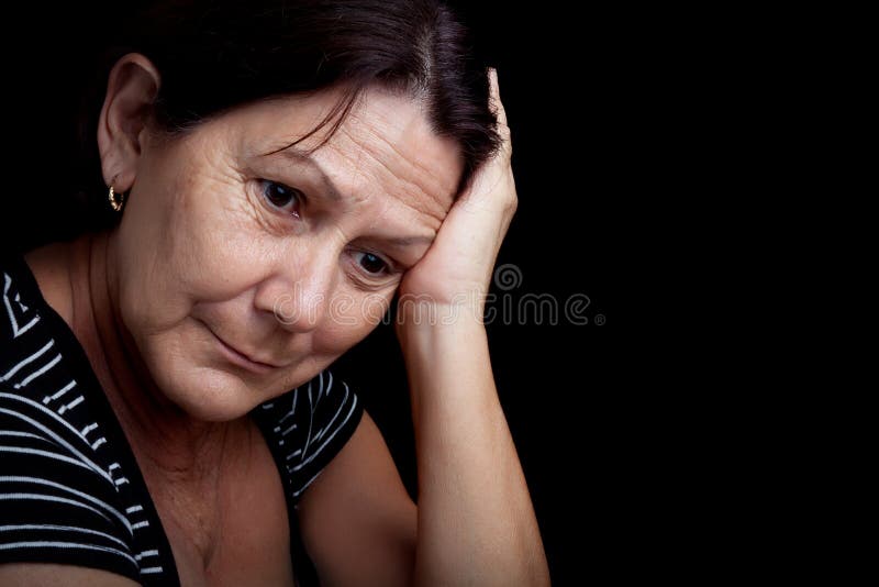 Portrait of a very sad and depressed older woman suffering from stress or a strong headache isolated on black. Portrait of a very sad and depressed older woman suffering from stress or a strong headache isolated on black