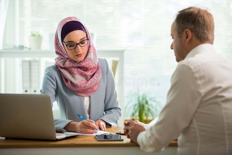 Mulher ? moda no hijab que faz a conversa??o na mesa com homem imagem de stock Mulher ? moda no hijab que faz a conversa??o na mesa com homem imagem de stock