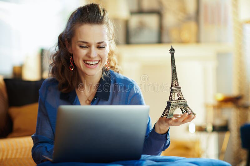 Mulher moderna feliz com a lembran?a da torre Eiffel usando o port?til foto de stock royalty free Mulher moderna feliz com a lembran?a da torre Eiffel usando o port?til foto de stock royalty free
