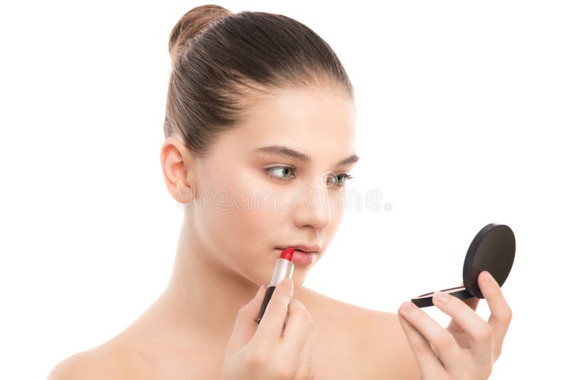 Mulher moreno nova com a cara limpa perfeita que aplica o batom usando o espelho Isolado em um branco foto de stock Mulher moreno nova com a cara limpa perfeita que aplica o batom usando o espelho Isolado em um branco foto de stock