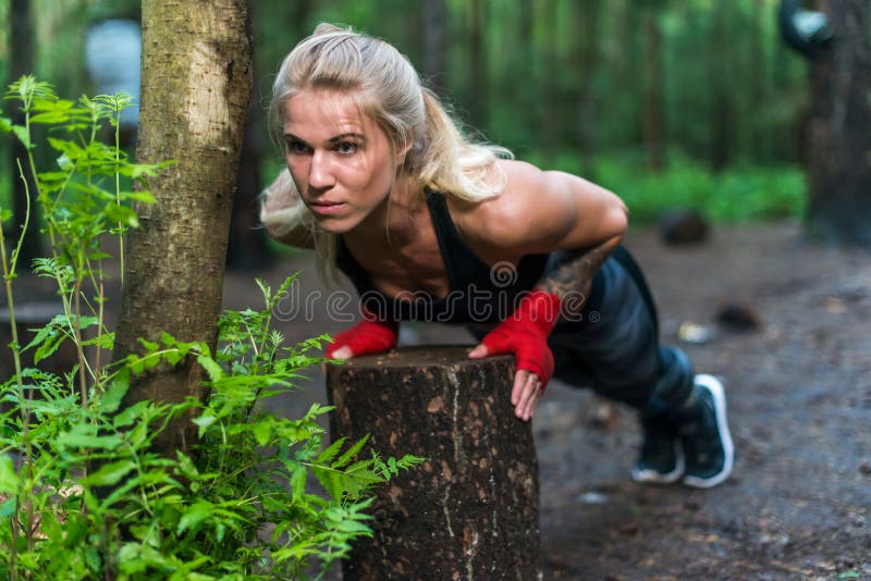 A mulher muscular que faz impulso-UPS na rua do parque dá certo imagem de stock A mulher muscular que faz impulso-UPS na rua do parque dá certo imagem de stock
