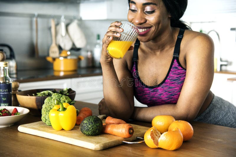 A mulher negra está bebendo o suco de laranja imagens de stock royalty free A mulher negra está bebendo o suco de laranja imagens de stock royalty free