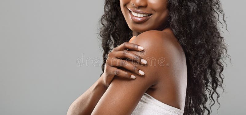 Mulher negra não reconhecível desfrutando sua pele lisa sobre fundo cinza