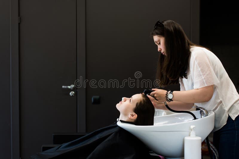 A mulher no cabeleireiro que obtém lhe o cabelo lavou e enxaguou o sentimento visivelmente boa foto de stock A mulher no cabeleireiro que obtém lhe o cabelo lavou e enxaguou o sentimento visivelmente boa foto de stock
