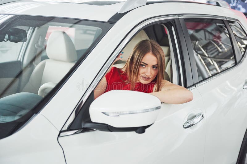 A mulher no carro interno mantém a roda girar em torno dos passageiros de vista de sorriso no taxista da ideia do banco traseiro imagens de stock A mulher no carro interno mantém a roda girar em torno dos passageiros de vista de sorriso no taxista da ideia do banco traseiro imagens de stock
