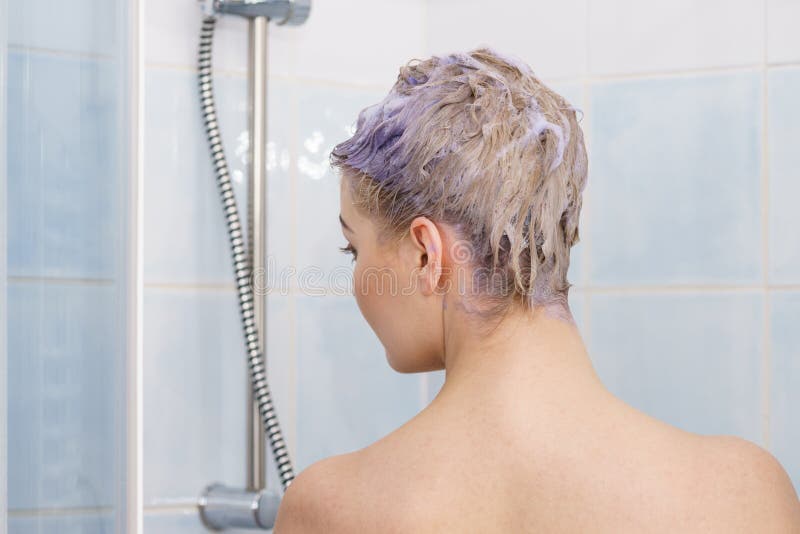 Mulher no chuveiro com espuma colorida no cabelo imagem de stock