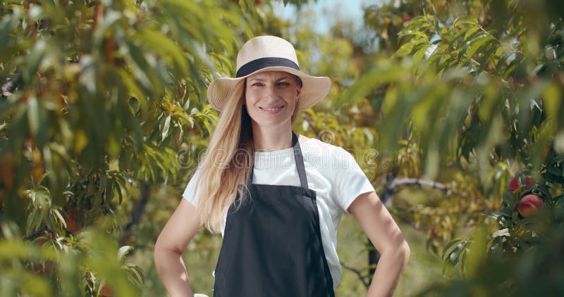 Mulher no verão que se posou com uma câmera no jardim de pêssego