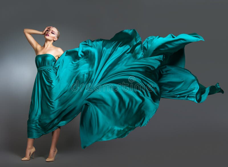 Mulher no vestido de seda que acena no vento Pano de voo e de vibração do vestido sobre o fundo cinzento imagem de stock Mulher no vestido de seda que acena no vento Pano de voo e de vibração do vestido sobre o fundo cinzento imagem de stock