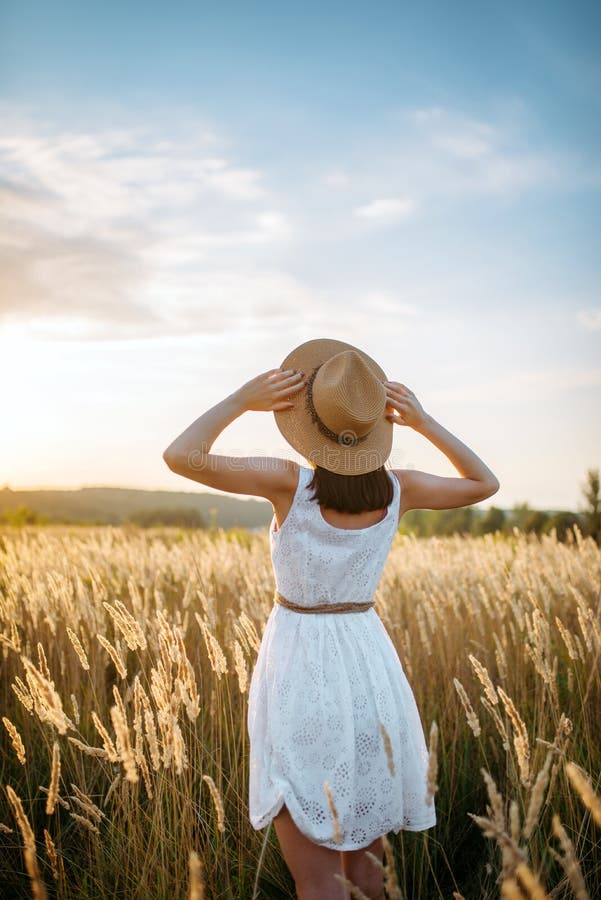 Mulher no vestido que anda no campo de trigo no por do sol imagens de stock royalty free Mulher no vestido que anda no campo de trigo no por do sol imagens de stock royalty free