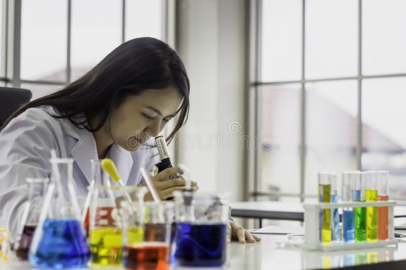 Mulher nova do químico que olha através do microscópio, trabalhando no laboratório, testes químicos no laboratório, conceito para fotos de stock royalty free Mulher nova do químico que olha através do microscópio, trabalhando no laboratório, testes químicos no laboratório, conceito para fotos de stock royalty free