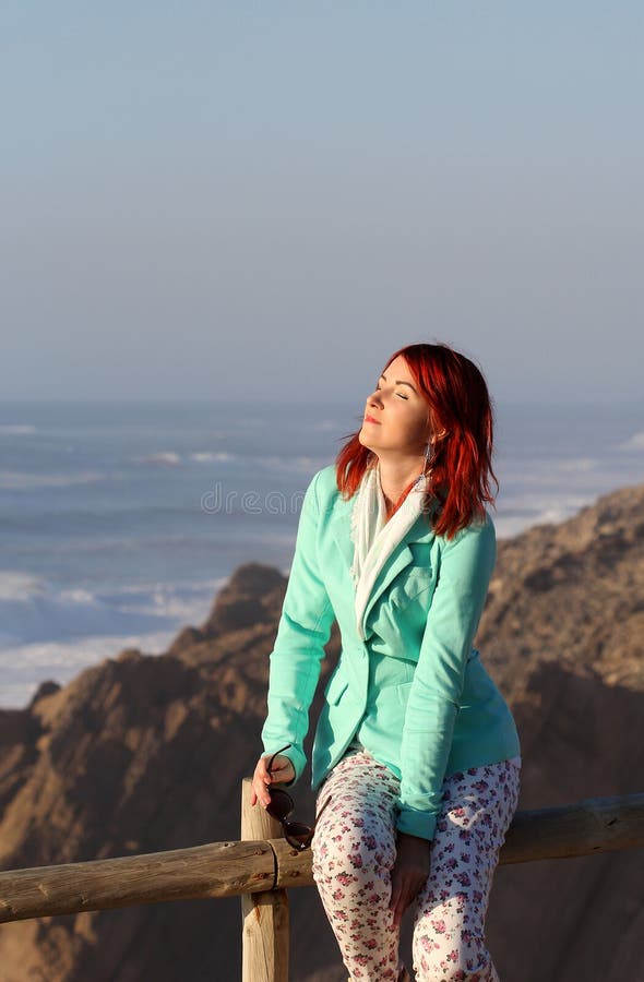 A mulher nova do ruivo que aprecia a luz solar no litoral imagens de stock A mulher nova do ruivo que aprecia a luz solar no litoral imagens de stock