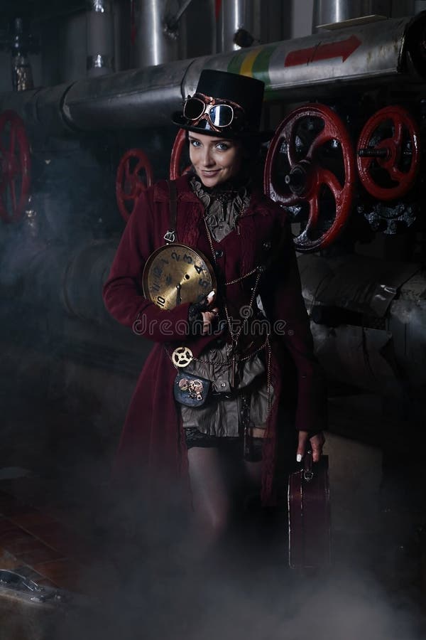 Mulher nova do steampunk com uma mala de viagem e uma face do relógio imagens de stock Mulher nova do steampunk com uma mala de viagem e uma face do relógio imagens de stock