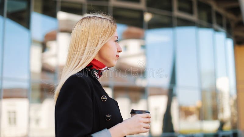 A mulher nova do transgender anda com uma xícara de café ao longo da parede do espelho fora