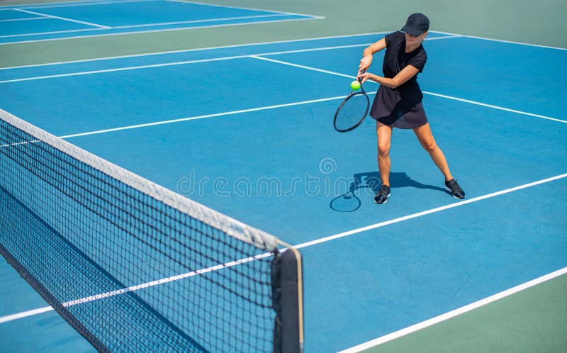 Mulher nova dos esportes que joga o tênis no campo de tênis azul fotos de stock Mulher nova dos esportes que joga o tênis no campo de tênis azul fotos de stock