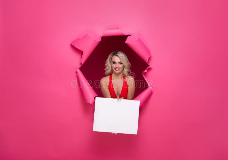 Mulher nova e bonita no vestido cor-de-rosa que guarda a bandeira de papel sobre o fundo de papel rasgado St Dia do ` s do Valent imagem de stock Mulher nova e bonita no vestido cor-de-rosa que guarda a bandeira de papel sobre o fundo de papel rasgado St Dia do ` s do Valent imagem de stock