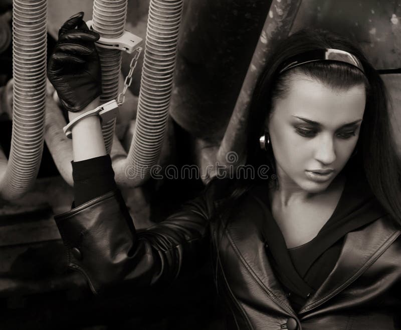 Mulher nova no revestimento de couro com algemas fotografia de stock Mulher nova no revestimento de couro com algemas fotografia de stock