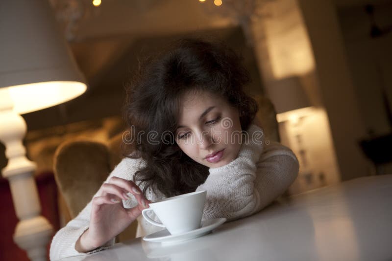 Mulher nova que aprecia o café do latte no café fotografia de stock royalty free