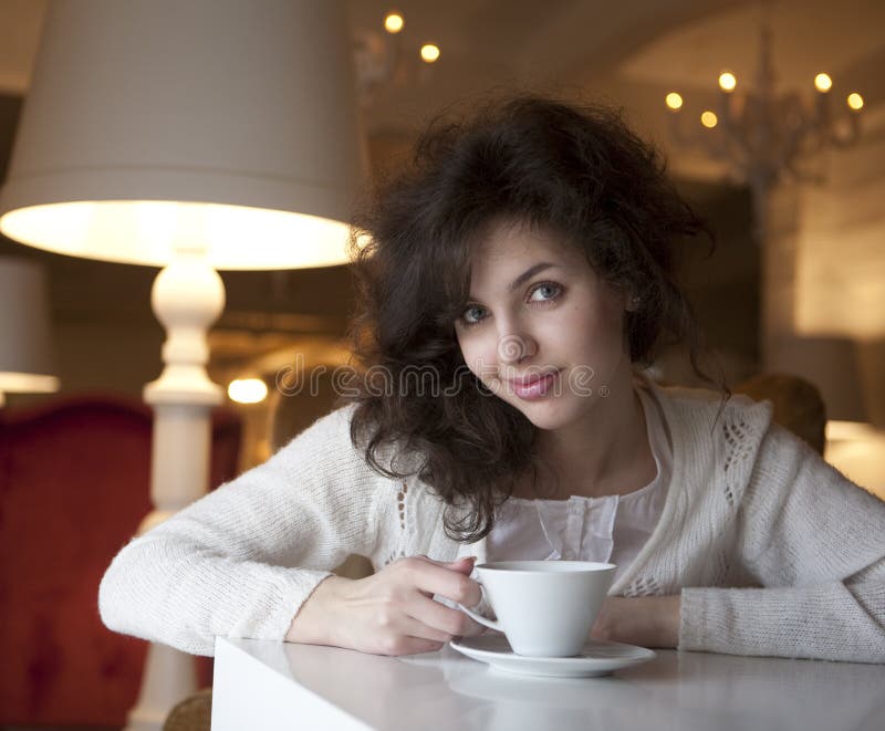 Mulher nova que aprecia o café do latte no café fotos de stock royalty free