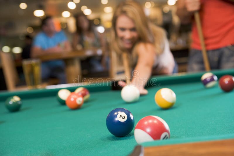 Young woman playing pool in a bar (focus on pool table). Young woman playing pool in a bar (focus on pool table)