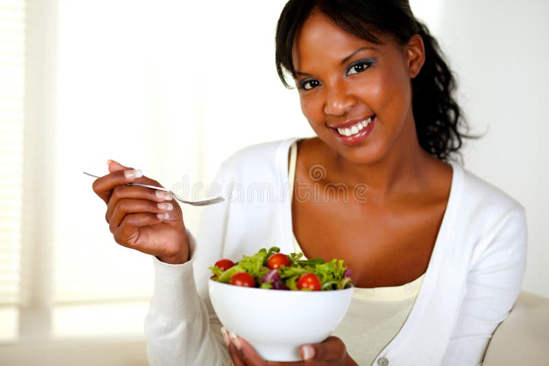 Mulher nova que olha o ao comer a salada imagem de stock Mulher nova que olha o ao comer a salada imagem de stock