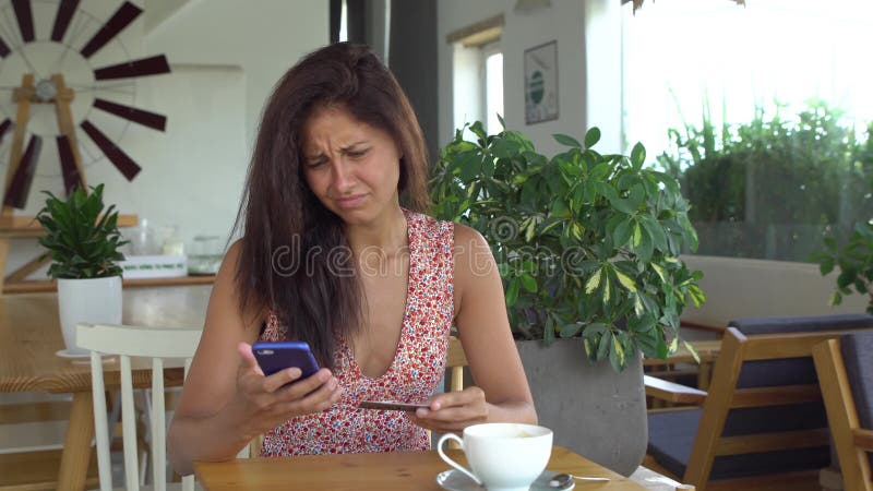 A mulher não pode fazer a compra com o cartão de crédito no telefone celular imagem de stock A mulher não pode fazer a compra com o cartão de crédito no telefone celular imagem de stock